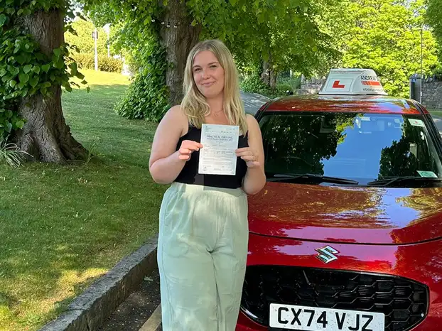 Young man in Rhyl next to driving instructor's car after completing driving lessons