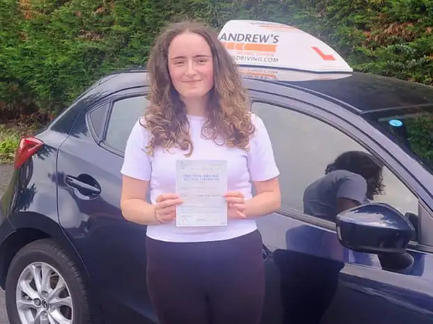 Young man in Rhyl next to driving instructor's car after completing driving lessons