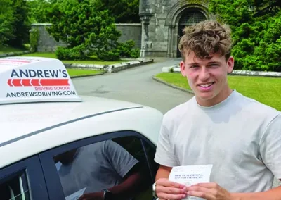 A young man with a driving test pass certificate outside Penrhyn Castle in Bangor