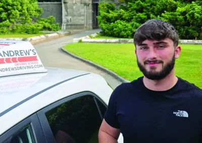 A young man with a driving test pass certificate outside Penrhyn Castle in Bangor