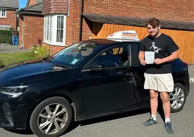 Young man posing by his driving instructors car after passing the driving test with Geraint
