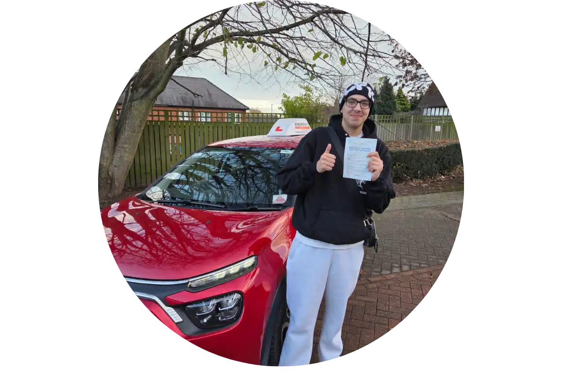 Learner driver holding pass certificate beside red car after passing their driving test near Bangor
