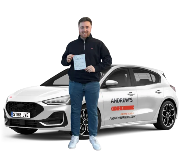 Learner driver holding a driving test pass certificate beside an Andrew’s driving school car in Rhyl