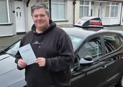 Dan showing his driving test pass next to Jamie Abbas driving school car