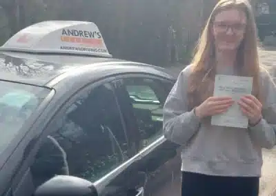 Isabella with her driving test pass certificate from Rhyl, Standing next to her instructors car in Colwyn Bay
