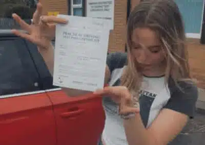 Jess holding her pass certificate after her driving test at Upton Driving Test Centre