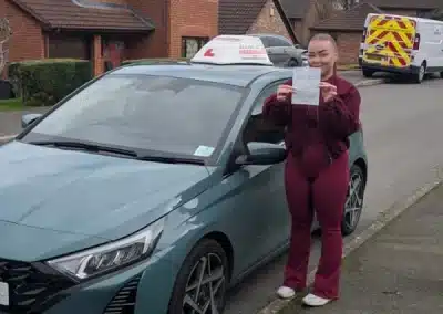 Morgan in Abergele with her new pass certificate, standing next to Jack's driving tuition car
