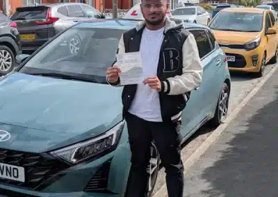 Ahsan in Colwyn Bay standing next to Jacks tuition car with his driving test pass certificate