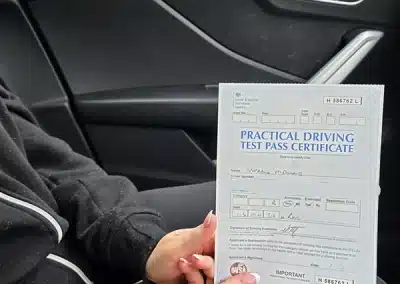 Steph holding her practical driving test pass certificate at Bangor Driving Test Centre after passing her driving test.