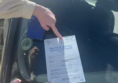 Amy holding her practical driving test pass certificate outside Rhyl Driving Test Centre after passing her driving test