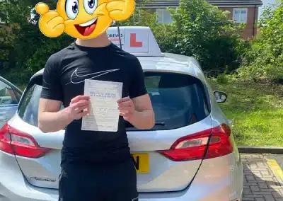 Ben holding his driving test pass certificate after passing in Wrexham with instructor Karl Whitefoot.