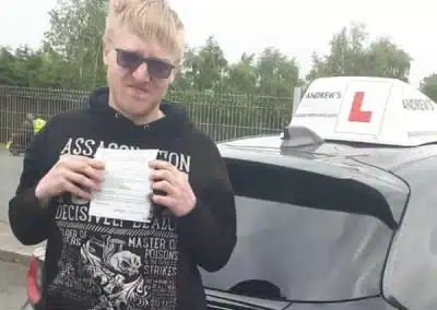 Ollie holding his driving test pass certificate beside Barry’s car after passing in Bangor with zero minors