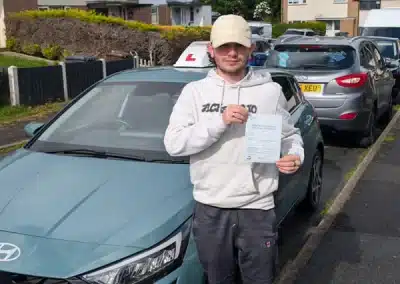 Rio standing beside Jack's Hyundai i20 in Colwyn Bay holding his driving test pass certificate after passing first time.