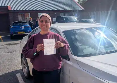 Soma holding her pass certificate beside Jimmy’s white car after passing her driving test in Rhyl.