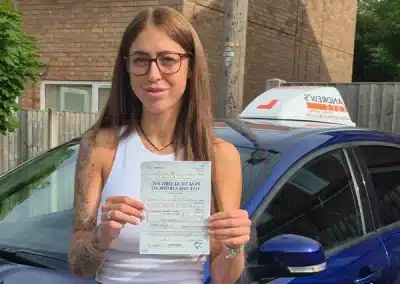 Courtney proudly holds her driving test pass certificate beside Craig’s learner car after passing at Wrexham Driving Test Centre.
