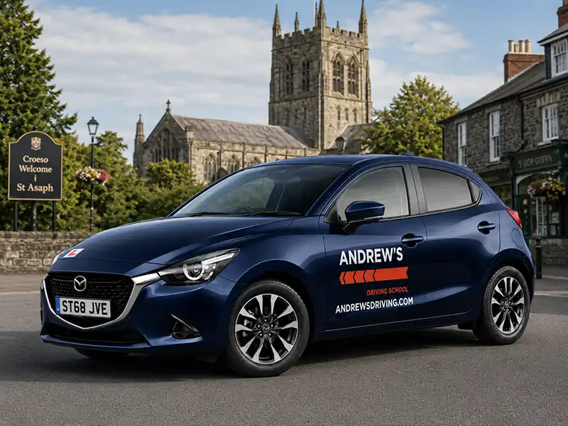 Dark blue Mazda 2 driving school car with Andrew's Driving branding in St Asaph