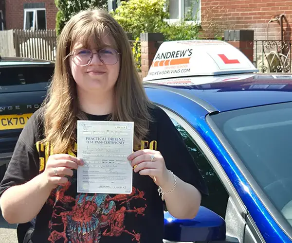 Angharad Williams holding her driving test pass certificate in Wrexham after passing with instructor Craig from Andrew's Driving School.