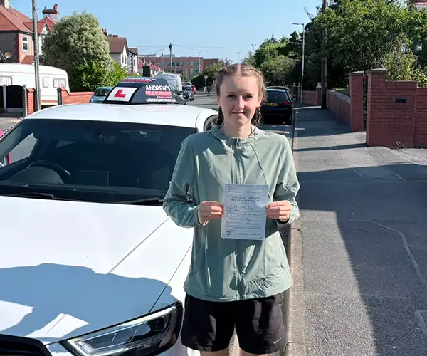 Evie Prior holding her driving test pass certificate in Rhyl after passing first time with instructor Marcus from Andrew's Driving School.