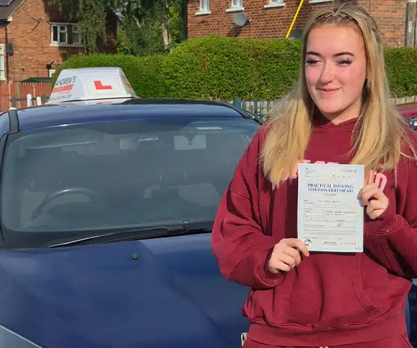 Lily holding her driving test certificate in front of Craig's tuition car after passing her test