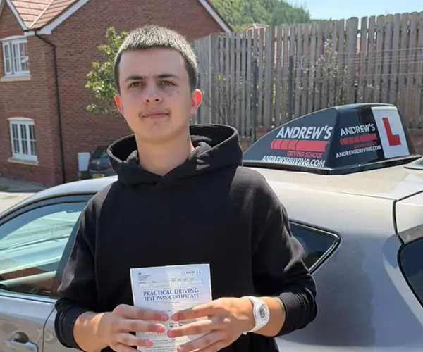Rhys Jones holding his driving test pass certificate at Rhyl Driving Test Centre after passing first time with instructor Ursula from Andrew's Driving School.
