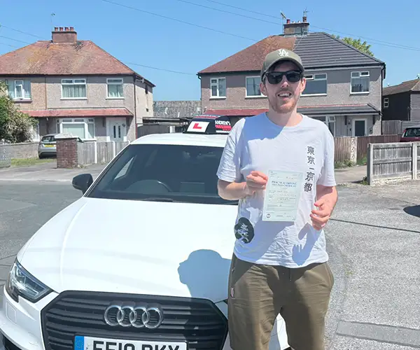 Ryan Lynch holding his driving test pass certificate in Rhyl after passing first time with instructor Marcus from Andrew's Driving School.