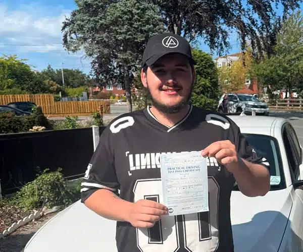 Josh with his driving test pass certificate in front of Ben's BMW.