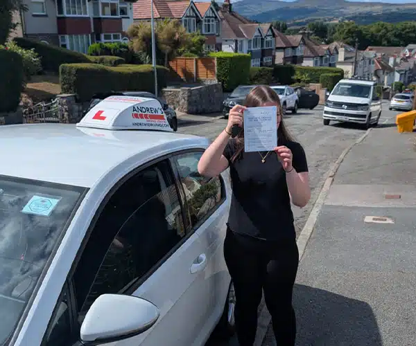 Yasmin standing near Tomas's VW Golf in Mochdre after passing her driving test in Rhyl.