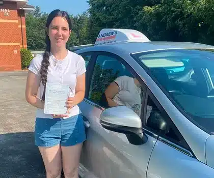 Caitlyn Jones in Wrexham Driving Test Centre Carpark holding her new pass certificate with Karl's silver Ford Fiesta tuition car