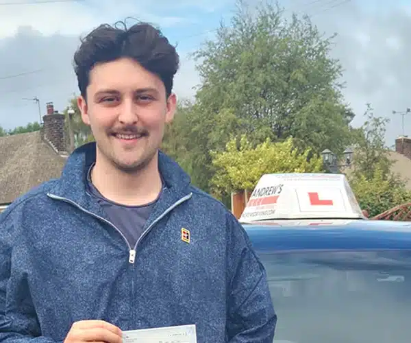 Connor at Wrexham Driving Test Centre  celebrating a first-time driving test pass in with instructor Craig Hughes's Andrew’s Driving School branded car.
