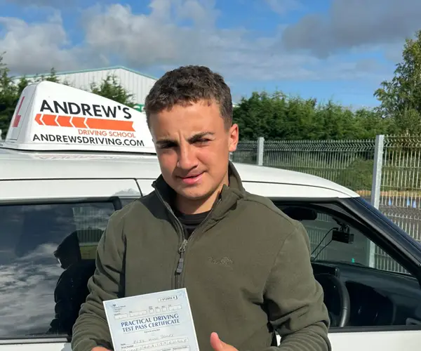 Ellis celebrating a first-time driving test pass in Bangor with instructor Robin Shepherds Andrew’s Driving School branded car.