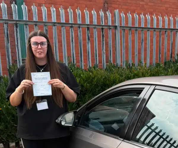 Emily in Rhyl Driving Test Centre  with Ursula's gold Toyota happy after passing her driving test