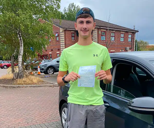 Evyn from Mold at Chester Driving Test Centre  celebrating a first-time driving test pass in with Andy Williams's driving tuition car.