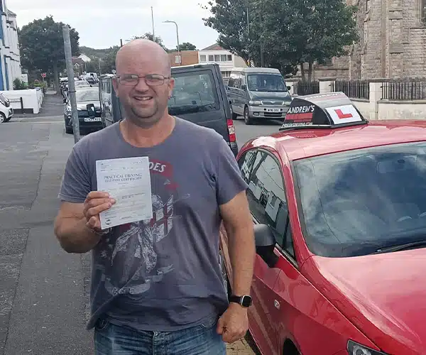 Joe Roberts after passing his driving test in Rhyl beside instructor John’s car