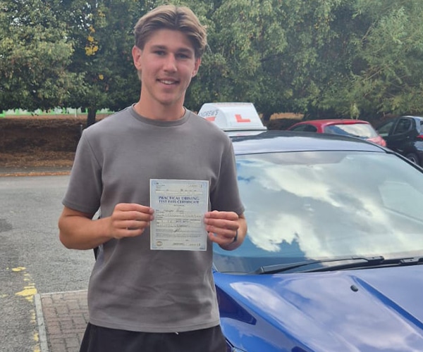 Kacper in Wrexham with Craig's blue Focus happy after passing his test in Wrexham Driving Test Centre