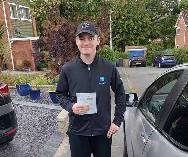 Joe Roberts after passing his driving test in Rhyl beside instructor John’s car