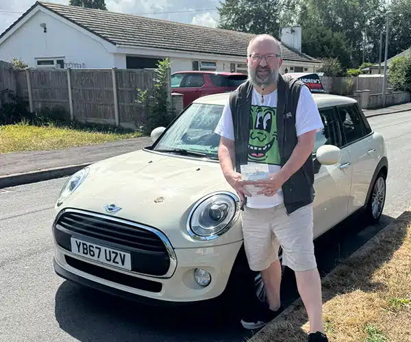 Philip Dempsey after passing his automatic driving test in Rhyl beside instructor Jimmy’s automatic Mini.