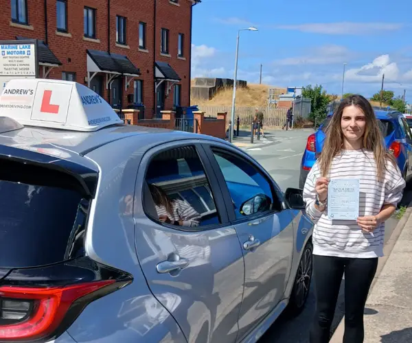 Victoria celebrating a first-time automatic driving test pass in Rhyl with instructor Barry Evans's Andrew’s Driving School branded car.
