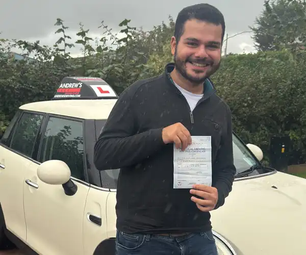 Dr Karim standing by Jimmy's automatic mini with his new driving test pass certificate in Rhyl Driving Test Centre car park