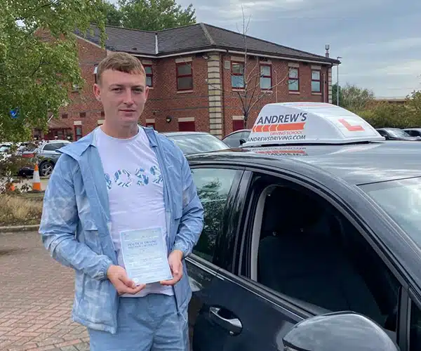 Harvey Williams from Buckley holding his driving test pass certificate at Chester Driving Test Centre beside instructor Andy Williams’ Volkswagen Golf.
