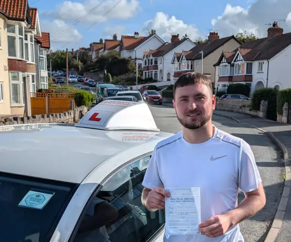 Lewis in Colwyn Bay holding his driving test pass certificate next to Tomas Kapus's White VW Golf