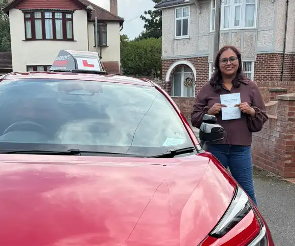 Ligi George holding her driving test pass certificate with Fiona's automatic Toyota in Rhyl