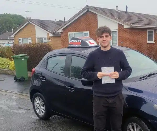 Robert holding his driving test pass certificate beside Mark Bilton’s Mazda 2 in Rhyl.