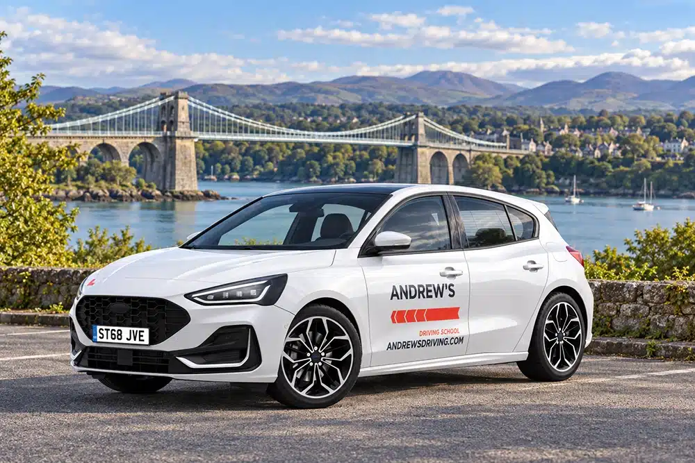 White Andrew’s Driving School Ford Focus with Menai Bridge in the background