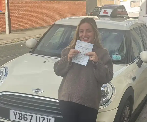 Ava Susan celebrating her first-time automatic driving test pass in Rhyl after learning with instructor Jimmy Garland.