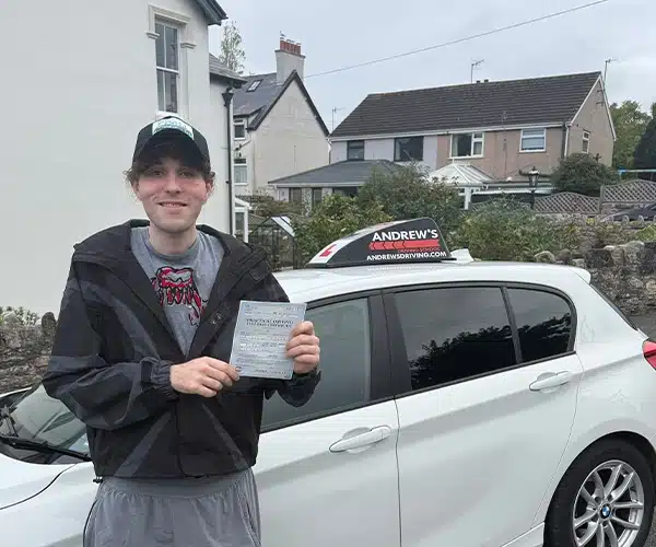 

Brody Maycock holding his driving test pass certificate beside Ben Vaughan-Jones’s Andrew’s Driving School car in Llandudno after passing with three minor faults.