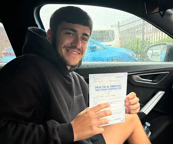 Jamie Hulme from Llandudno Junction celebrating his first-time automatic driving test pass in Rhyl after learning with instructor Ryan McCarley.