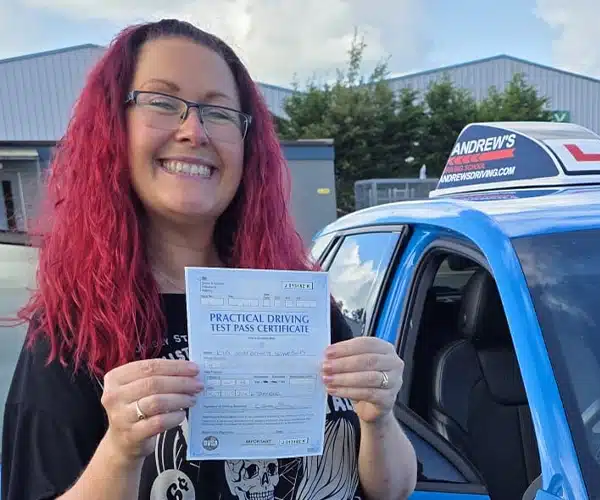 
Ria Simpson holding her pass certificate beside instructor Ryan McCarley’s Audi after passing her automatic driving test first time at Bangor Driving Test Centre.